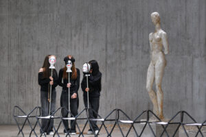 drei Schülerinnen auf der Bühne neben einer Lehmbruck-Skulptur