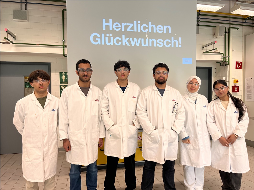 Schüler mit Kittel und Schutzbrille an der Uni